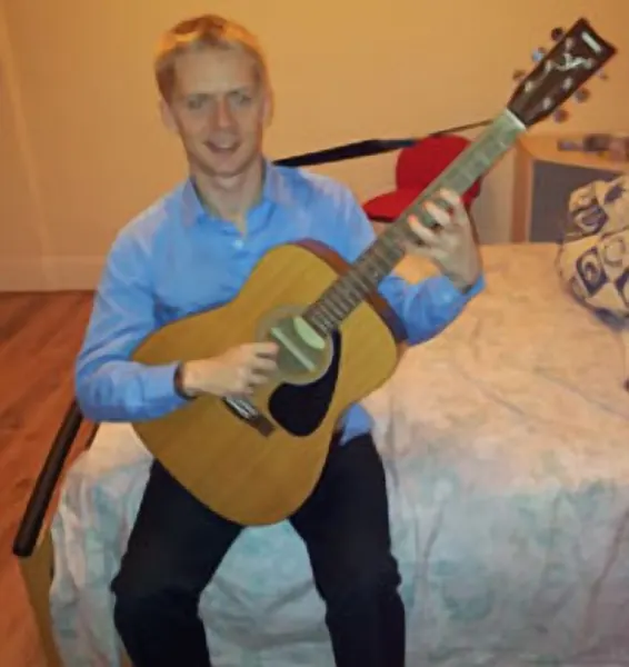 Daniel Bellington holding their acoustic guitar — Cool Gool Music guitar lessons, London SE16