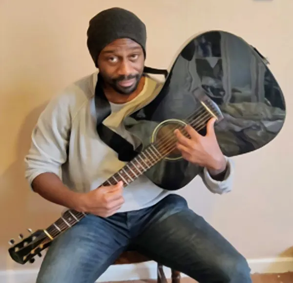 Michael Ahimah holding their acoustic guitar — Cool Gool Music guitar lessons, London SE16